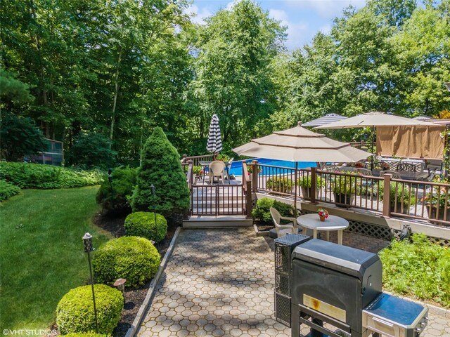 view of community with outdoor dining area, a patio area, a lawn, and a wooden deck