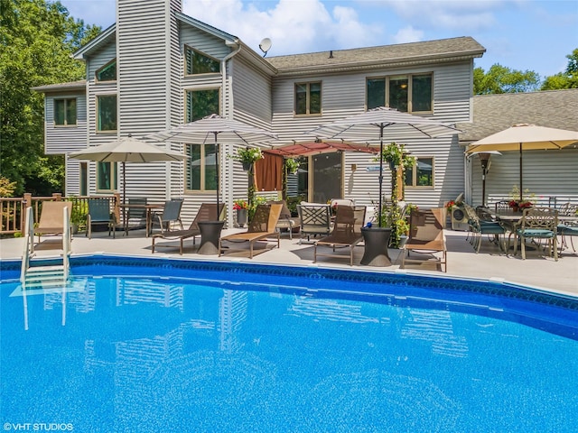 rear view of house with a patio, a chimney, and an outdoor pool