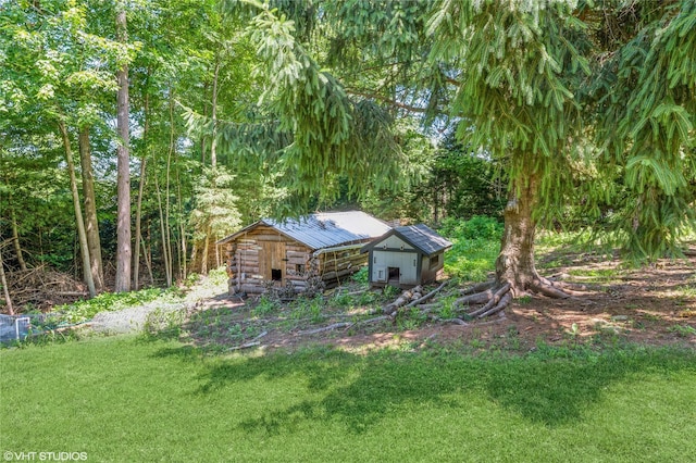 view of front of home featuring an outbuilding, a front yard, and log siding