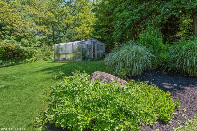 view of yard featuring a greenhouse and an outbuilding