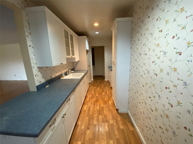 kitchen with light wood-type flooring, sink, and white cabinets