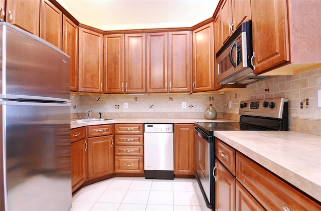 kitchen with tasteful backsplash, stainless steel appliances, sink, and light tile patterned floors