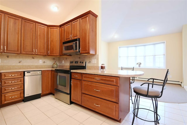 kitchen featuring lofted ceiling, a kitchen bar, tasteful backsplash, kitchen peninsula, and stainless steel appliances