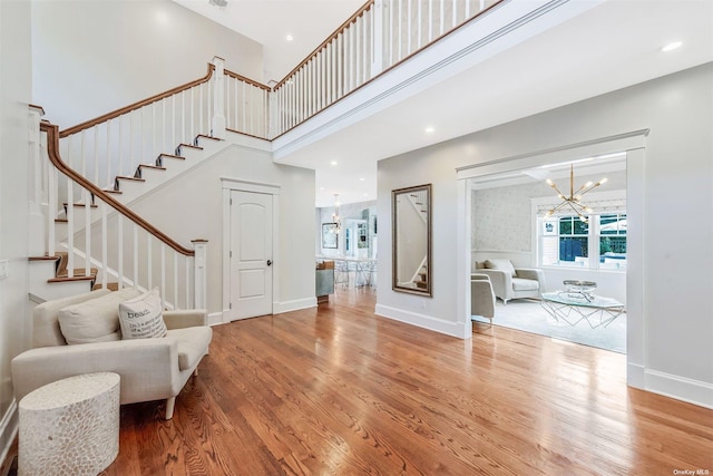 entryway featuring an inviting chandelier, a towering ceiling, and wood-type flooring