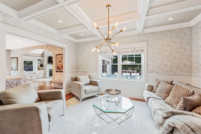 living room featuring coffered ceiling, a chandelier, light hardwood / wood-style flooring, ornamental molding, and beamed ceiling