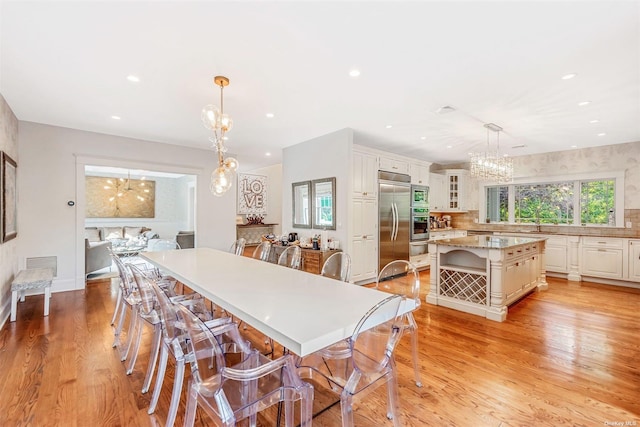 dining space with light wood-type flooring and a notable chandelier