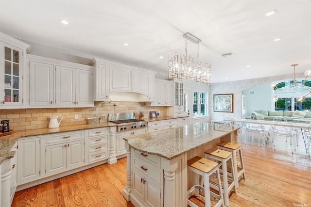 kitchen featuring pendant lighting, white cabinets, a kitchen breakfast bar, a center island, and light hardwood / wood-style flooring