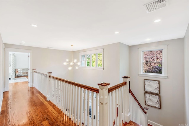 hallway with an inviting chandelier and light hardwood / wood-style flooring