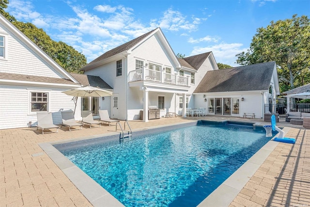 back of house featuring a balcony, a fenced in pool, and a patio