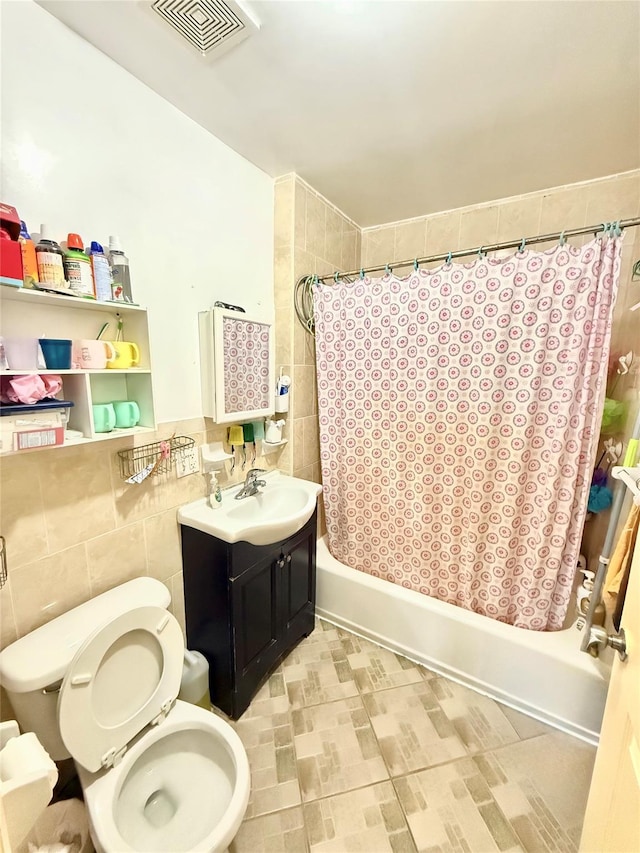 full bathroom with vanity, toilet, shower / bath combo with shower curtain, and tile walls