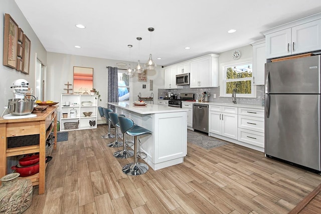 kitchen with white cabinetry, hanging light fixtures, stainless steel appliances, and a center island