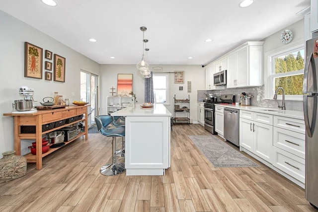 kitchen featuring pendant lighting, appliances with stainless steel finishes, a center island, and white cabinets