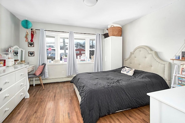 bedroom featuring a baseboard heating unit and dark wood-type flooring