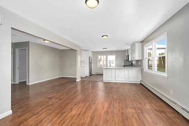 unfurnished living room with hardwood / wood-style flooring and a baseboard heating unit