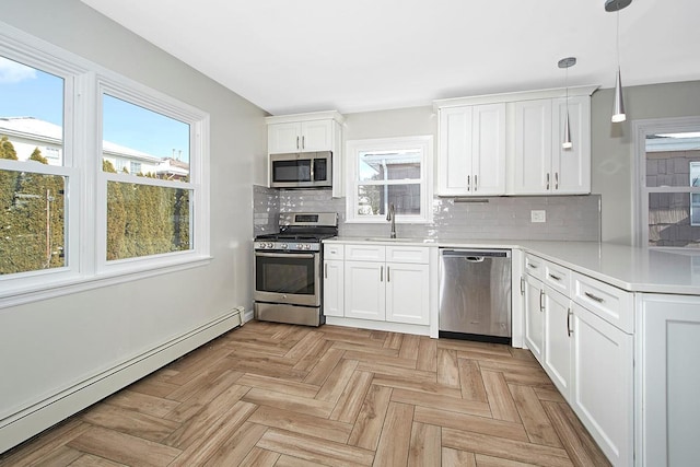 kitchen with hanging light fixtures, baseboard heating, appliances with stainless steel finishes, light parquet flooring, and white cabinets