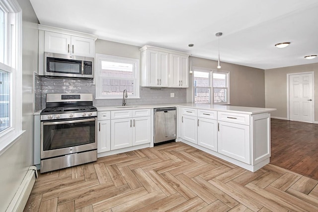 kitchen featuring white cabinetry, hanging light fixtures, baseboard heating, kitchen peninsula, and stainless steel appliances