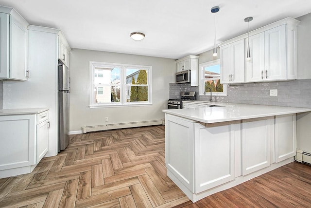 kitchen featuring white cabinetry, stainless steel appliances, decorative light fixtures, a baseboard radiator, and kitchen peninsula