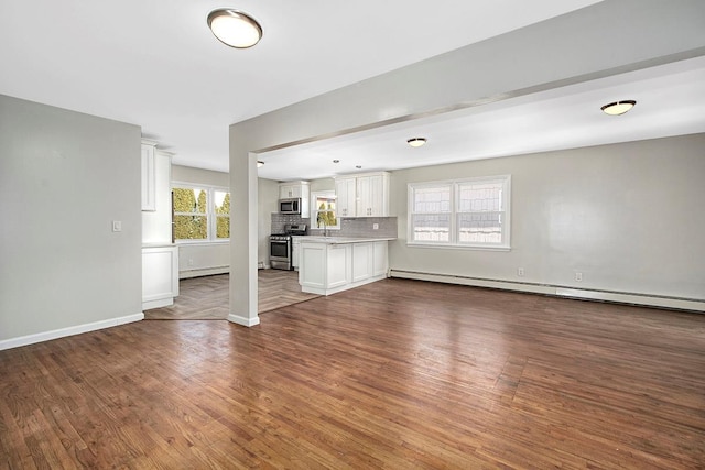 unfurnished living room with sink, a baseboard radiator, and dark hardwood / wood-style floors