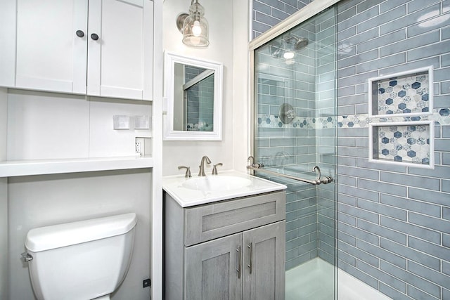 bathroom with vanity, toilet, and a shower with shower door