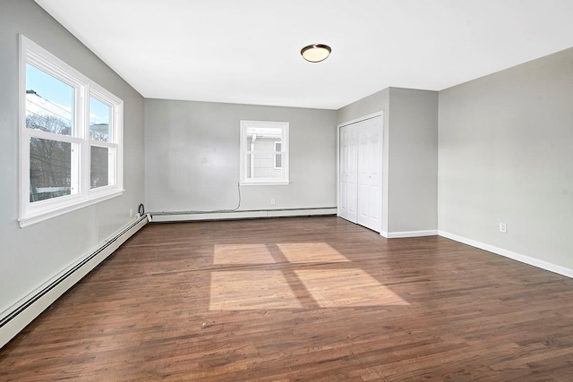 unfurnished bedroom featuring dark hardwood / wood-style floors, a closet, and a baseboard heating unit