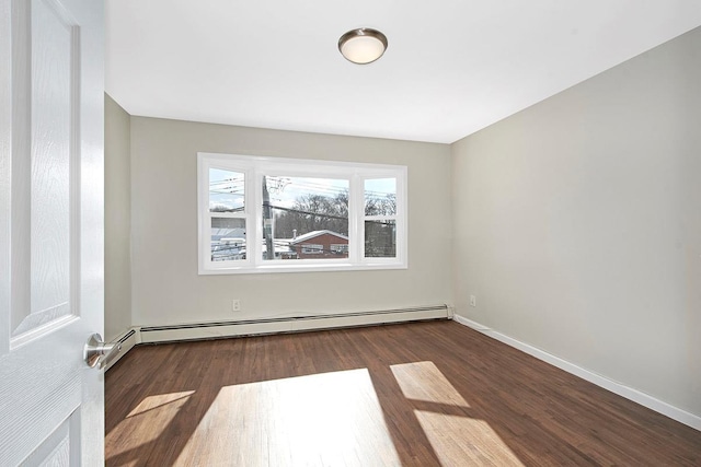 empty room with dark hardwood / wood-style flooring and a baseboard heating unit