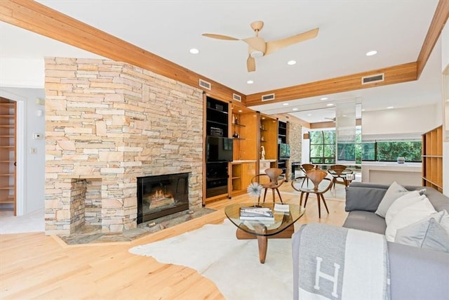 living room with hardwood / wood-style flooring, ceiling fan, and a fireplace