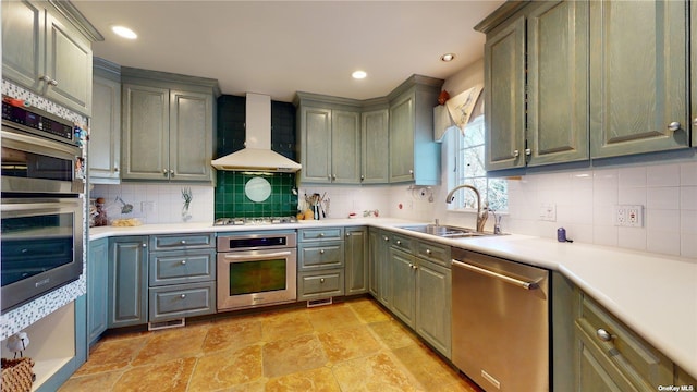 kitchen featuring wall chimney exhaust hood, appliances with stainless steel finishes, sink, and decorative backsplash