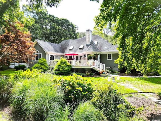 rear view of house featuring a deck and a lawn