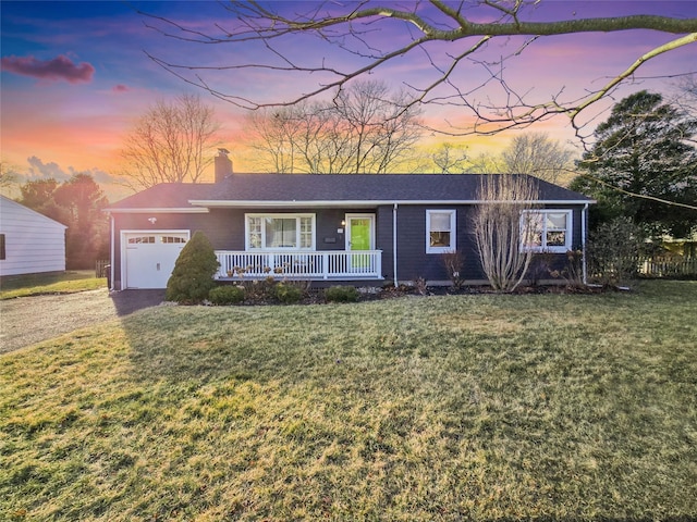 ranch-style home featuring a yard, a garage, and covered porch