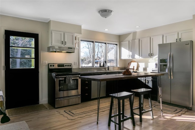 kitchen with ornamental molding, appliances with stainless steel finishes, white cabinets, and light hardwood / wood-style flooring