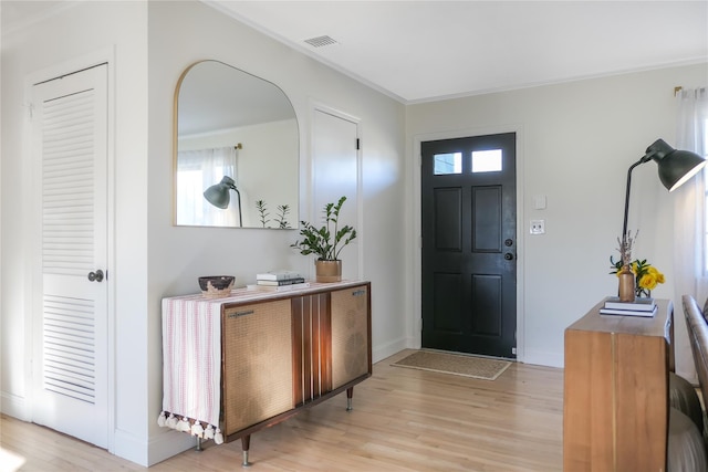 foyer with ornamental molding and light hardwood / wood-style flooring