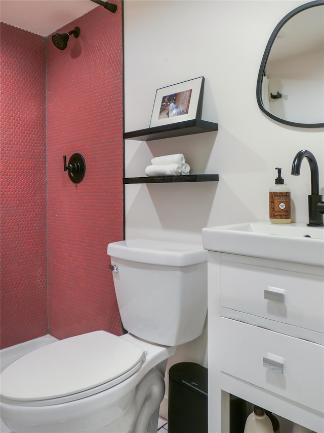 bathroom with vanity, toilet, and a tile shower