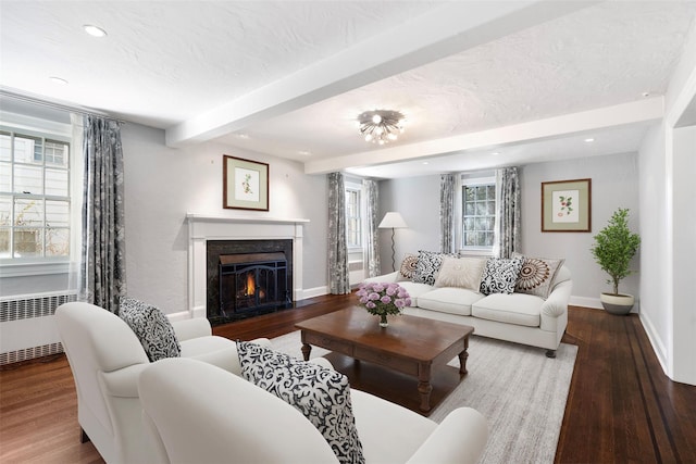 living room featuring beam ceiling, a high end fireplace, radiator heating unit, a textured ceiling, and hardwood / wood-style floors