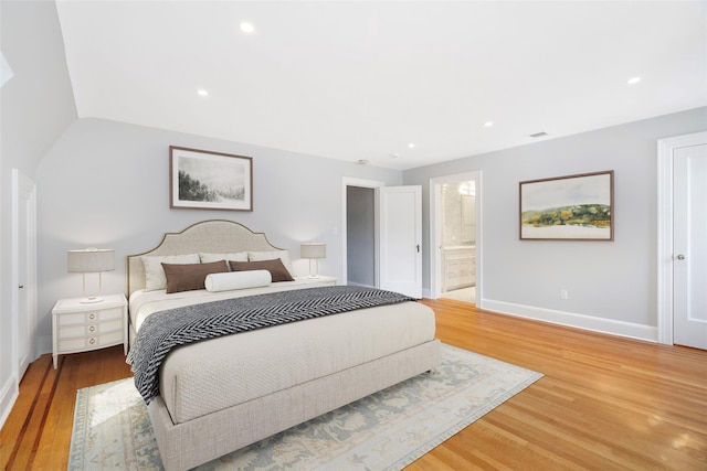 bedroom with hardwood / wood-style flooring and ensuite bath