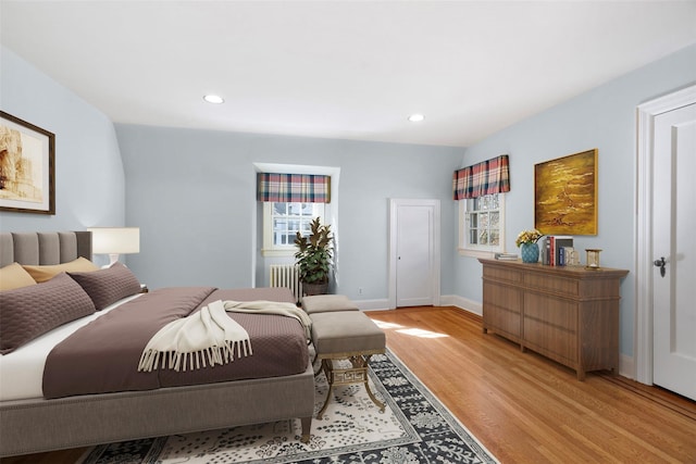 bedroom featuring multiple windows, radiator, and light hardwood / wood-style floors