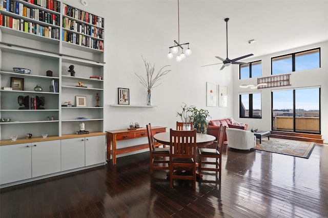 dining room with dark hardwood / wood-style floors, ceiling fan, and a towering ceiling