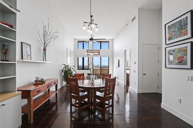 dining room with dark hardwood / wood-style flooring, a chandelier, and a high ceiling