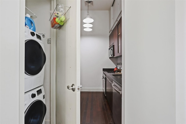 laundry room featuring dark wood-type flooring and stacked washer / dryer