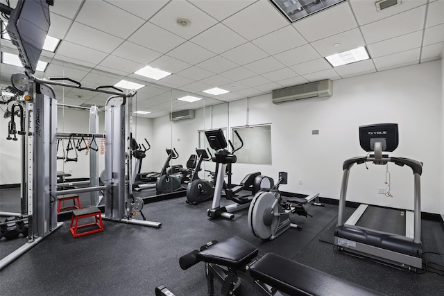 gym featuring a paneled ceiling and a wall mounted AC