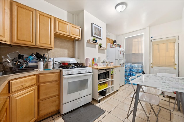 kitchen featuring light tile patterned flooring, sink, light brown cabinets, and white appliances