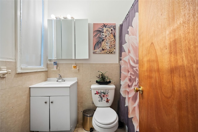 bathroom with vanity, toilet, and tile walls