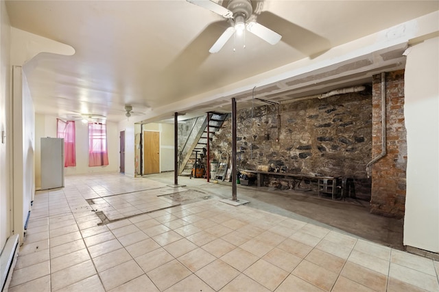 basement with light tile patterned flooring, ceiling fan, and baseboard heating