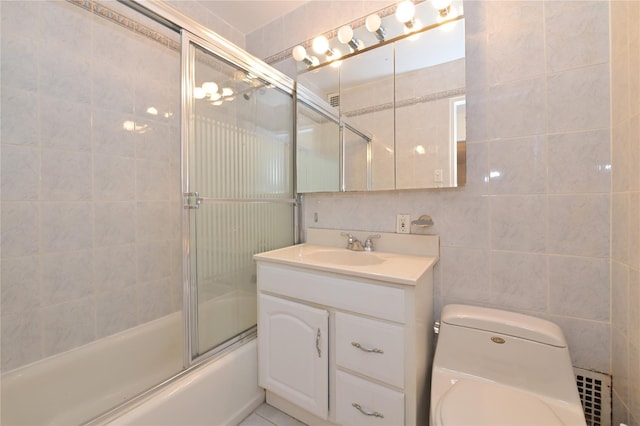 full bathroom with bath / shower combo with glass door, tile walls, vanity, and toilet