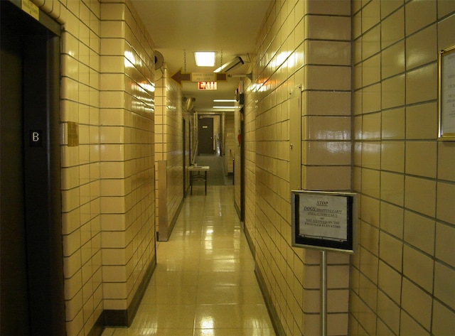 hallway with tile walls, light tile patterned floors, and a package area