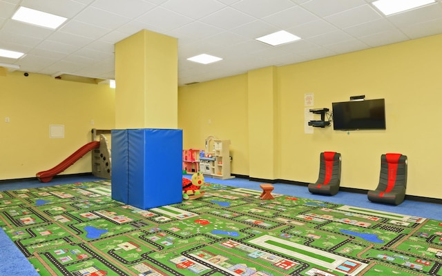 rec room featuring dark colored carpet and a drop ceiling