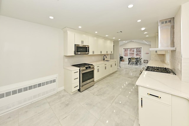 kitchen with sink, white cabinetry, radiator heating unit, stainless steel appliances, and island exhaust hood