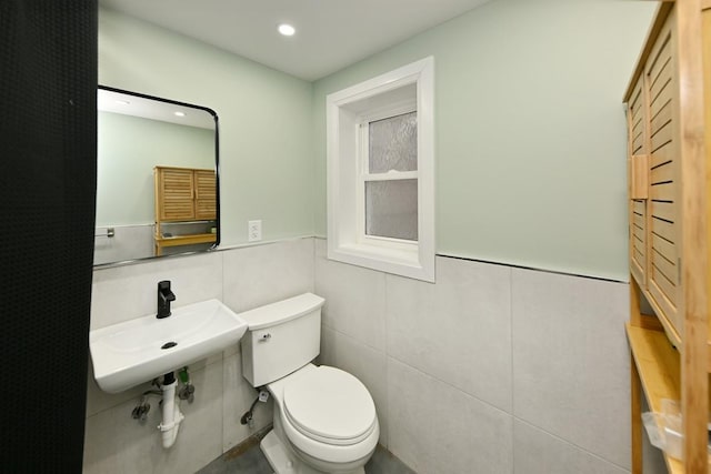 bathroom featuring tile walls, sink, and toilet