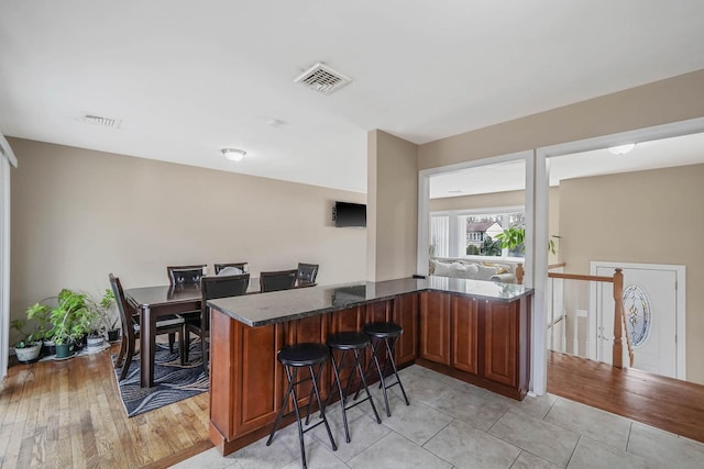 bar with light tile patterned flooring and dark stone counters