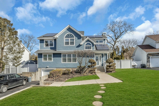 view of front of property with a garage, a front yard, and solar panels