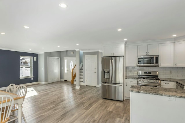 kitchen featuring white cabinetry, stainless steel appliances, stone countertops, and decorative backsplash